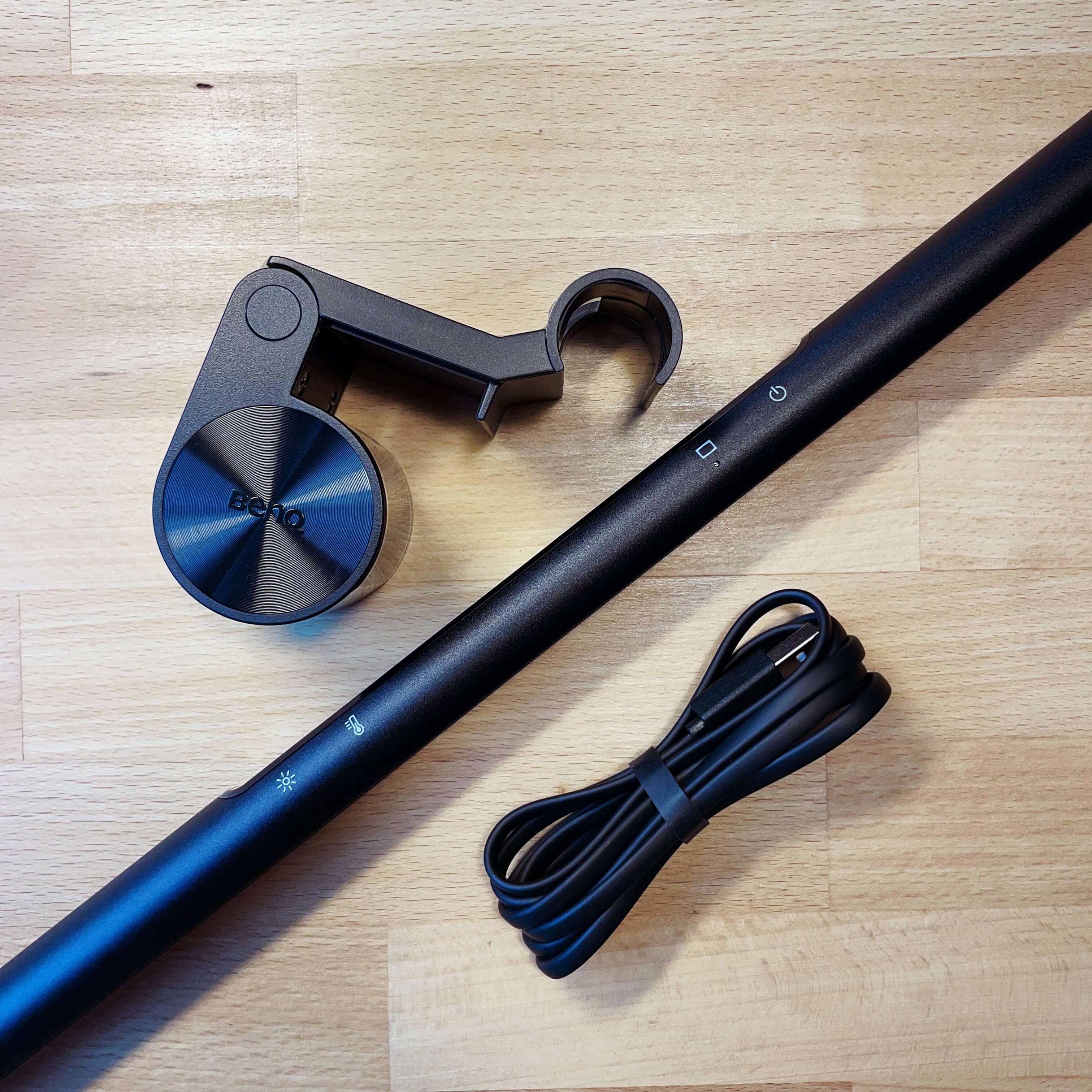 All three parts of the lamp (clip, lamp, USB-C) cable layed out on a light brown wodden table.